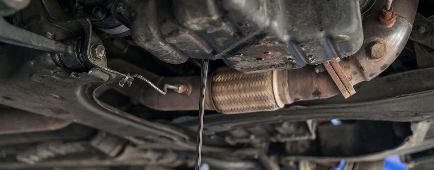 A close up shows oil being drained from an oil pan.