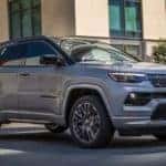 A silver 2022 Jeep Compass Sport is shown parked on the side of a city street.