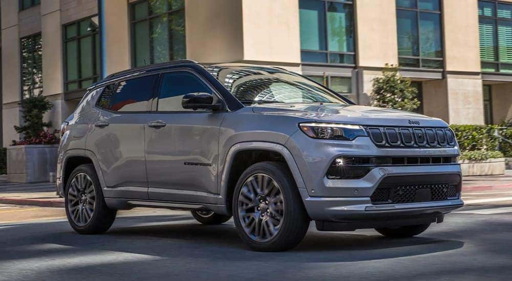 A silver 2022 Jeep Compass Sport is shown parked on the side of a city street.