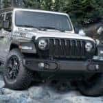 A silver 2020 Jeep Wrangler Willys is shown driving on a rocky path.