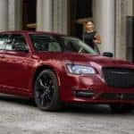A red 2021 Chrysler 300 Touring L is shown parked in front of stone pillars.