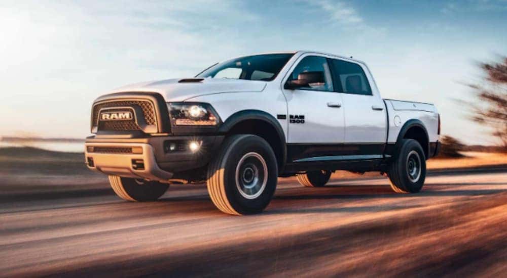 A white 2018 Ram 1500 is shown driving on an empty highway.