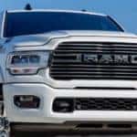 A close up shows the grille and headlights of a white 2021 Ram 2500 Laramie.