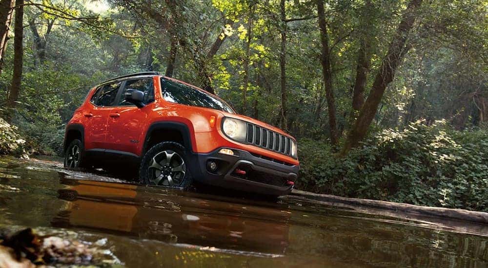An orange 2021 Jeep Renegade is shown off-roading after searching 'Jeep service near me.'
