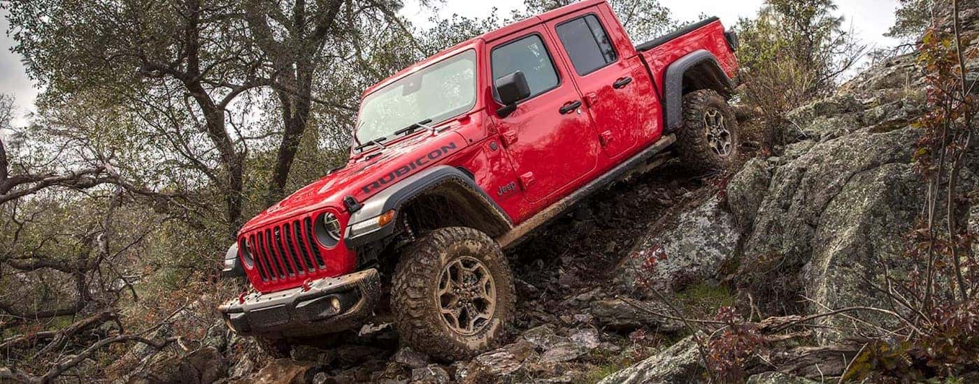 A red 2022 Jeep Gladiator Rubicon is shown off-roading on a rocky trail.