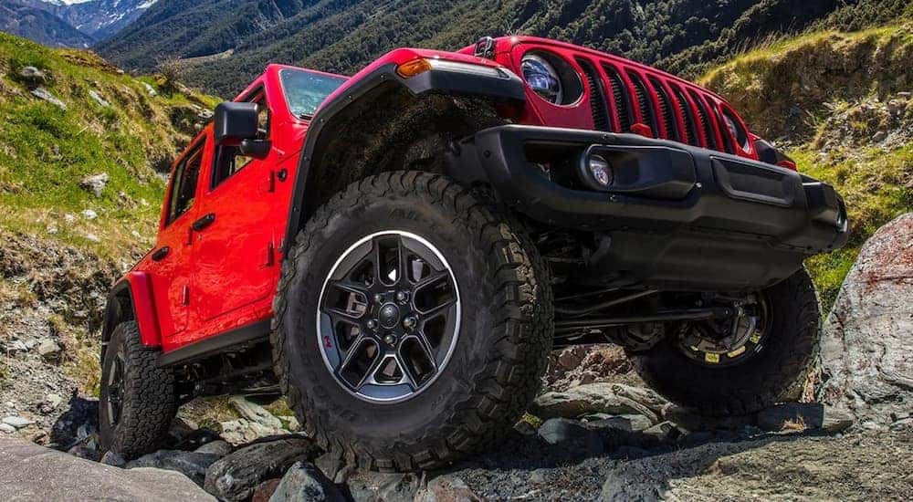A red 2021 Jeep Wrangler Rubicon is shown off-roading on a rocky trail.