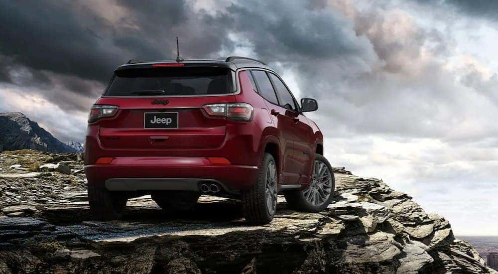 A red 2022 Jeep Compass is shown from the rear parked on rocks after looking at Jeep dealers in Colorado Springs.