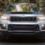A silver 2022 Jeep Grand Cherokee 4xe is shown from the front driving on an open road.