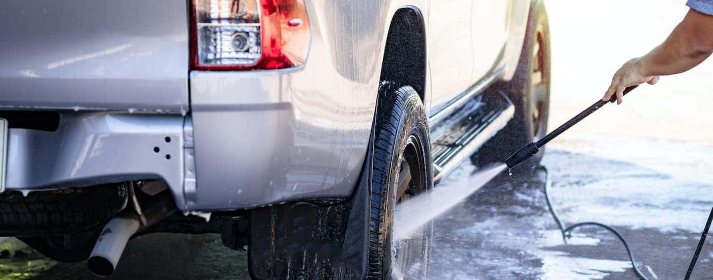 A close up shows a truck wheel being pressure washed.