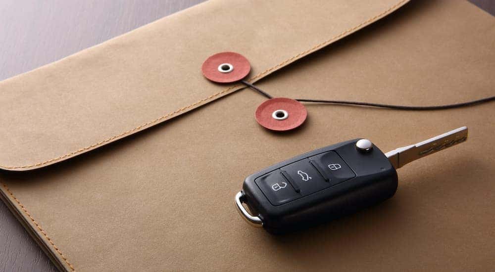 A car key is shown resting on top of a closed envelope.