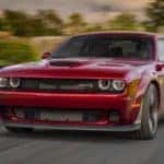 A red Certified Pre-Owned 2018 Dodge Challenger Hellcat is shown from the front while driving down the road after