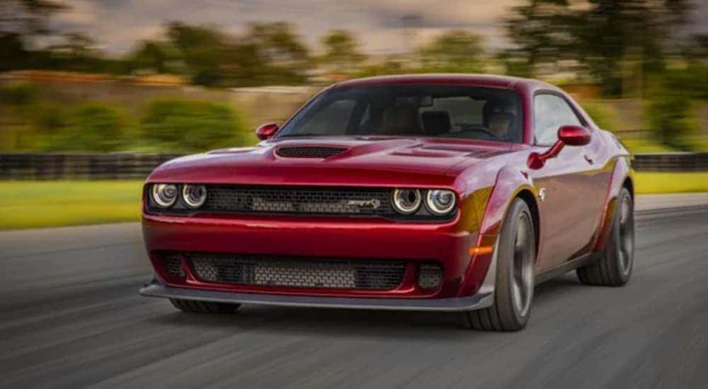 A red Certified Pre-Owned 2018 Dodge Challenger Hellcat is shown from the front while driving down the road after