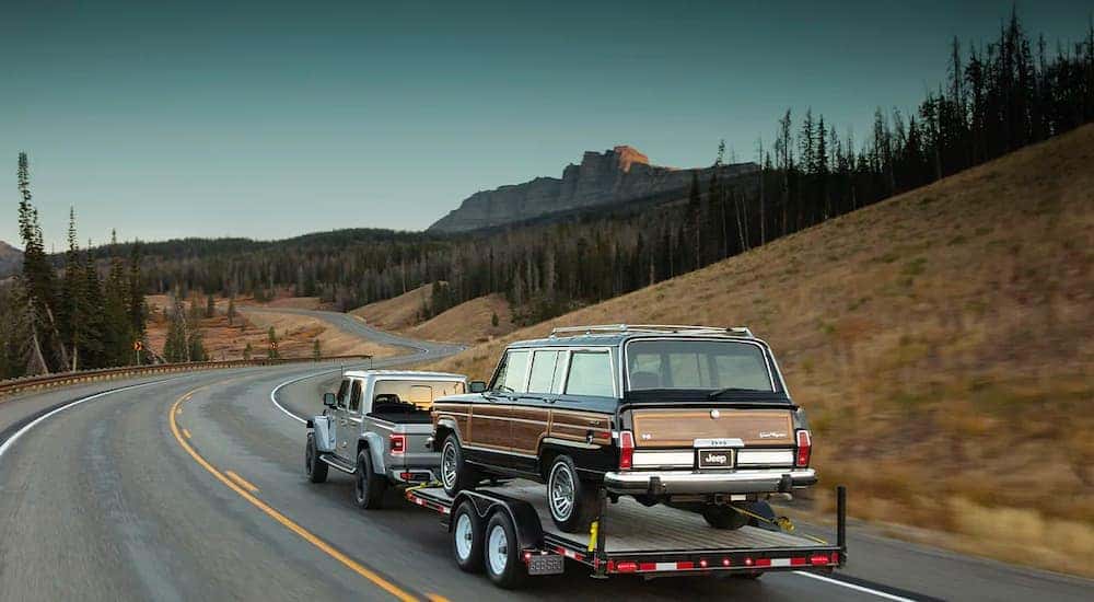 A silver 2021 Jeep Gladiator is shown towing a Wagoneer on the way to get Jeep parts in Colorado Springs.