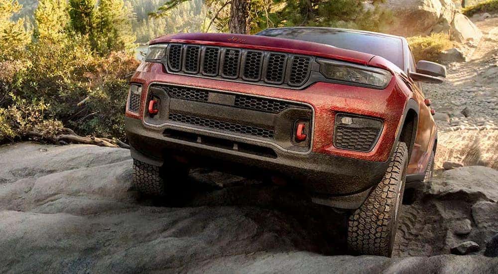 A maroon 2022 Jeep Grand Cherokee Trailhawk is shown driving off-road.