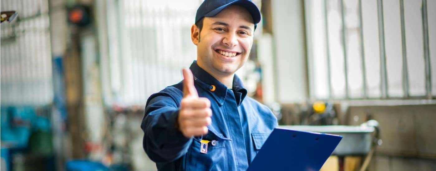 A mechanic is shown giving a thumbs up at a Jeep repair shop.