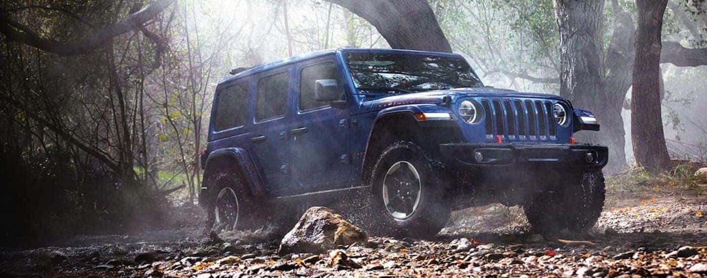 A blue 2020 Jeep Wrangler Unlimited is shown from the side parked in the forest after leaving a Colorado Springs used Jeep dealer.