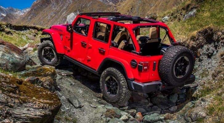 A red 2020 Jeep Wrangler Unlimited is shown from the rear off-roading.