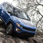 A blue 2022 Jeep Compass Trailhawk is shown from the front off-roading.