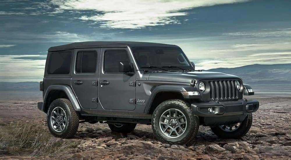 A silver 2021 Jeep Wrangler is shown from the side parked in the mountains after leaving a Jeep service center.