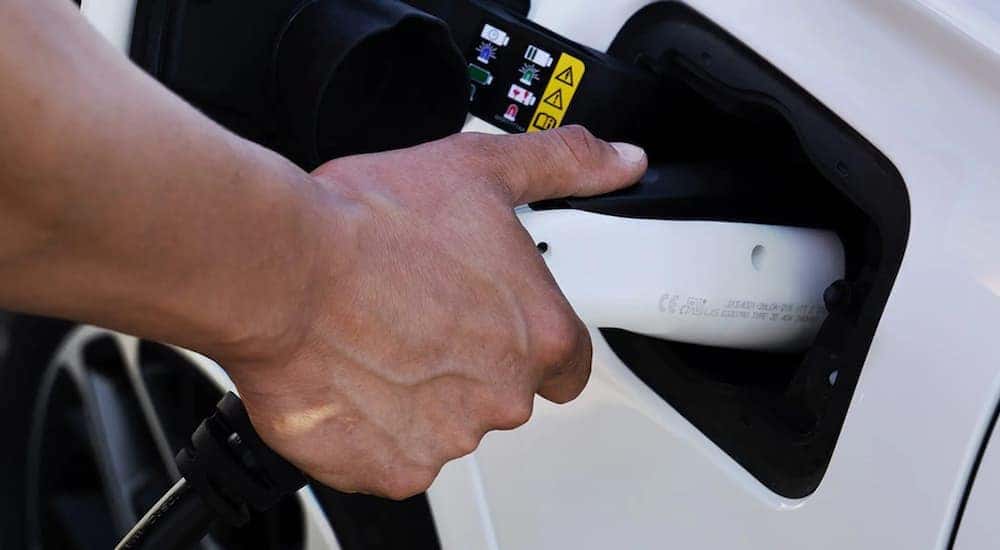 A person is shown charging a Jeep Grand Cherokee 4xe for sale.
