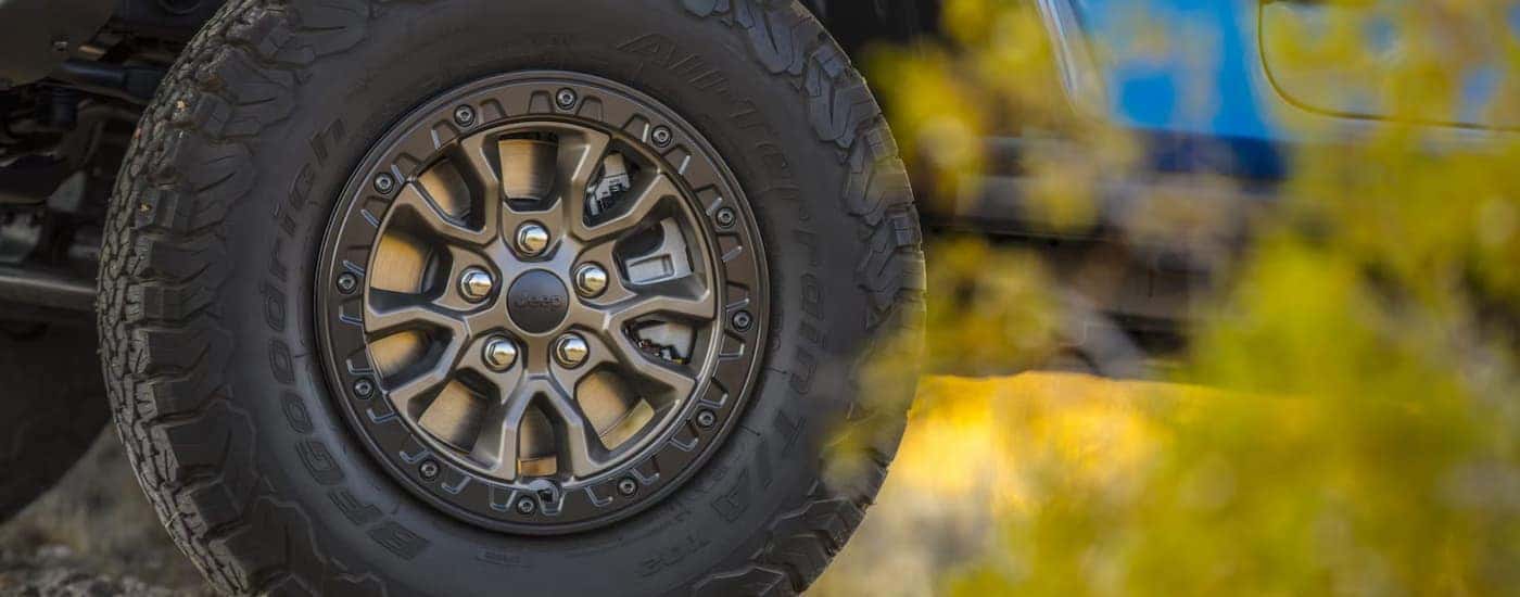 A close up shows the wheel and tire on a blue 2022 Jeep Wrangler Rubicon 392 Unlimited.
