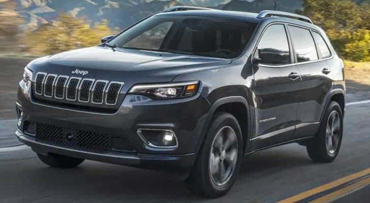 A black 2021 Jeep Cherokee is shown driving on an open road.