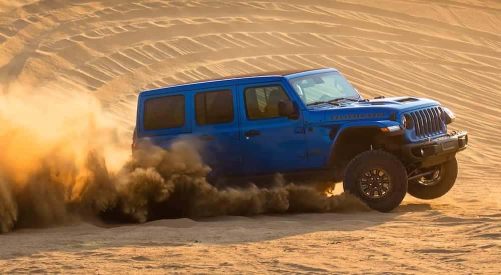 A blue 2022 Jeep Wrangler Rubicon 392 is shown from the side while driving through the desert.