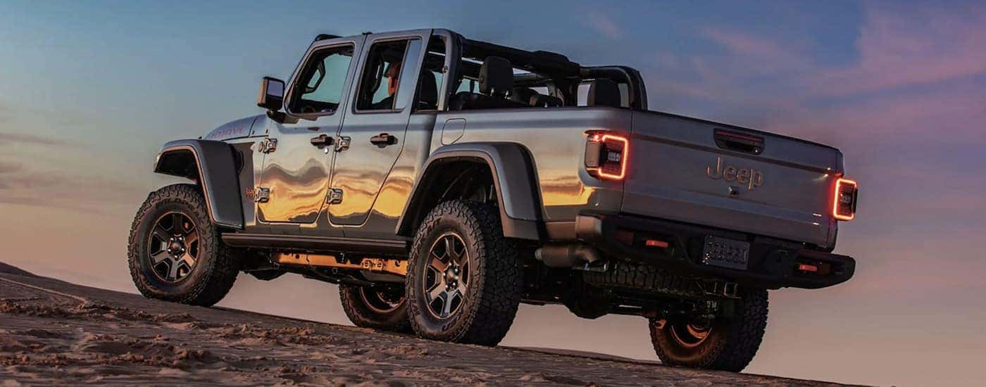 A grey 2023 Jeep Gladiator is shown from the rear at sunset.