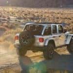A silver 2023 Jeep Wrangler 4xe is shown from the rear at an angle after leaving a Denver Jeep dealer.