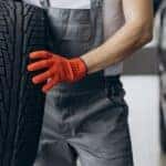 A mechanic is shown holding a tire while performing a tire service near you.