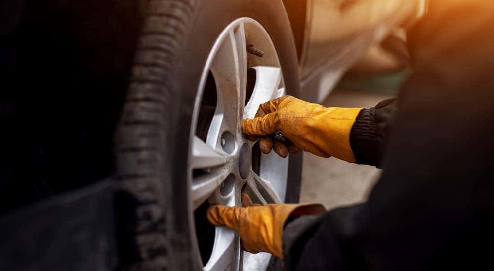 A close up of a mechanic is shown performing a tire service near you.