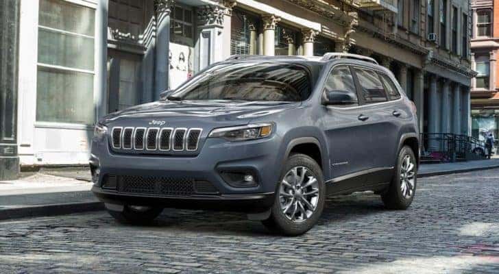 A grey 2021 Jeep Cherokee is shown parked on a cobble stone street.