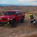 A red 2022 Jeep Gladiator Rubicon is shown from the front while parked off-road.