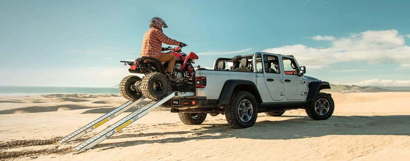 A person is shown driving a ATV into the bed of a white 2022 Jeep Gladiator Rubicon.