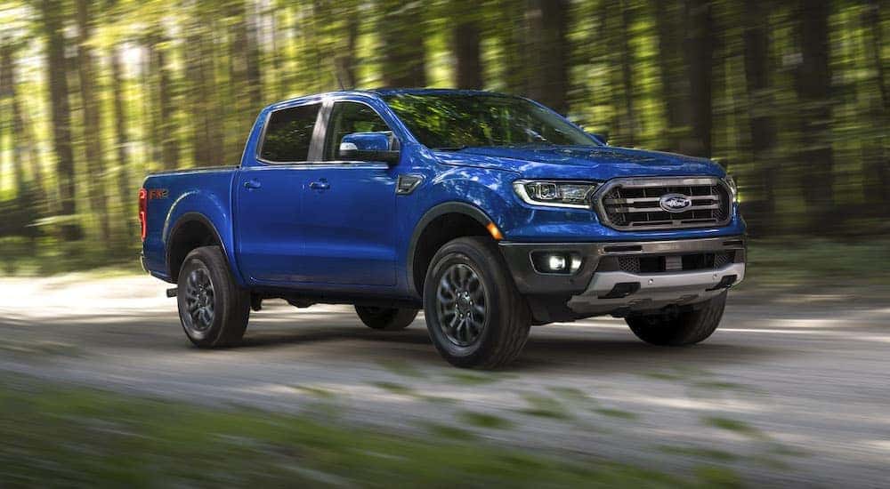A used ford trucks near you, a blue 2019 Ford Ranger is shown from the front driving on a dirt road.