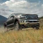 A grey 2020 Ford Ranger is shown from the front driving through a field.