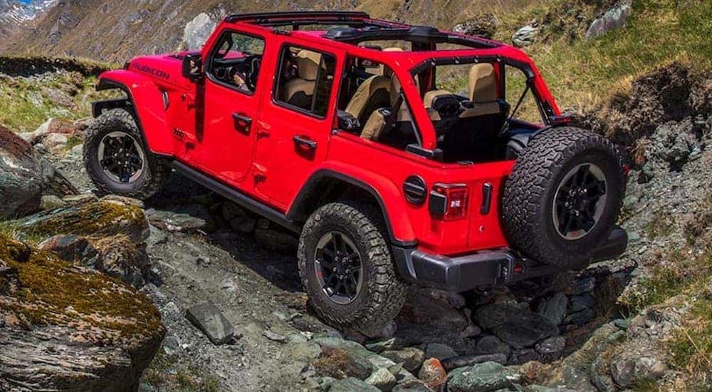 A red 2020 Jeep Wrangler is shown from the rear at an angle in a rocky area after leaving a dealer that has a used Jeep Wrangler for sale near Fountain, CO.