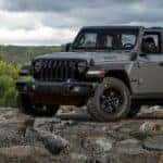 A gray 2022 Jeep Wrangler Willys is shown from the front at an angle in a rocky area.