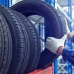 A mechanic is shown taking a tire off of a rack.