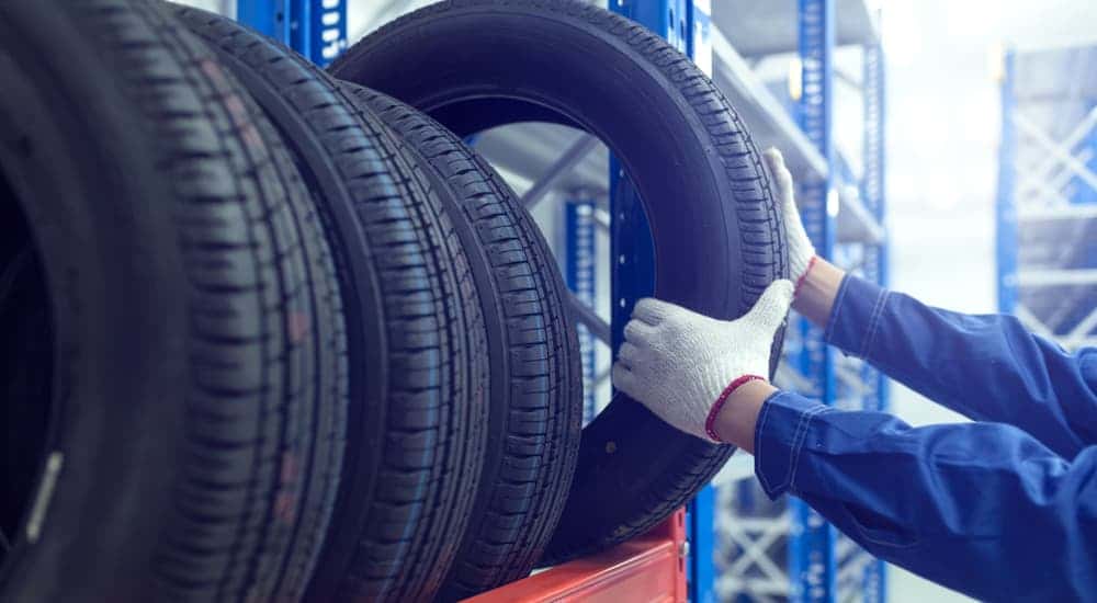 A mechanic is shown taking a tire off of a rack.
