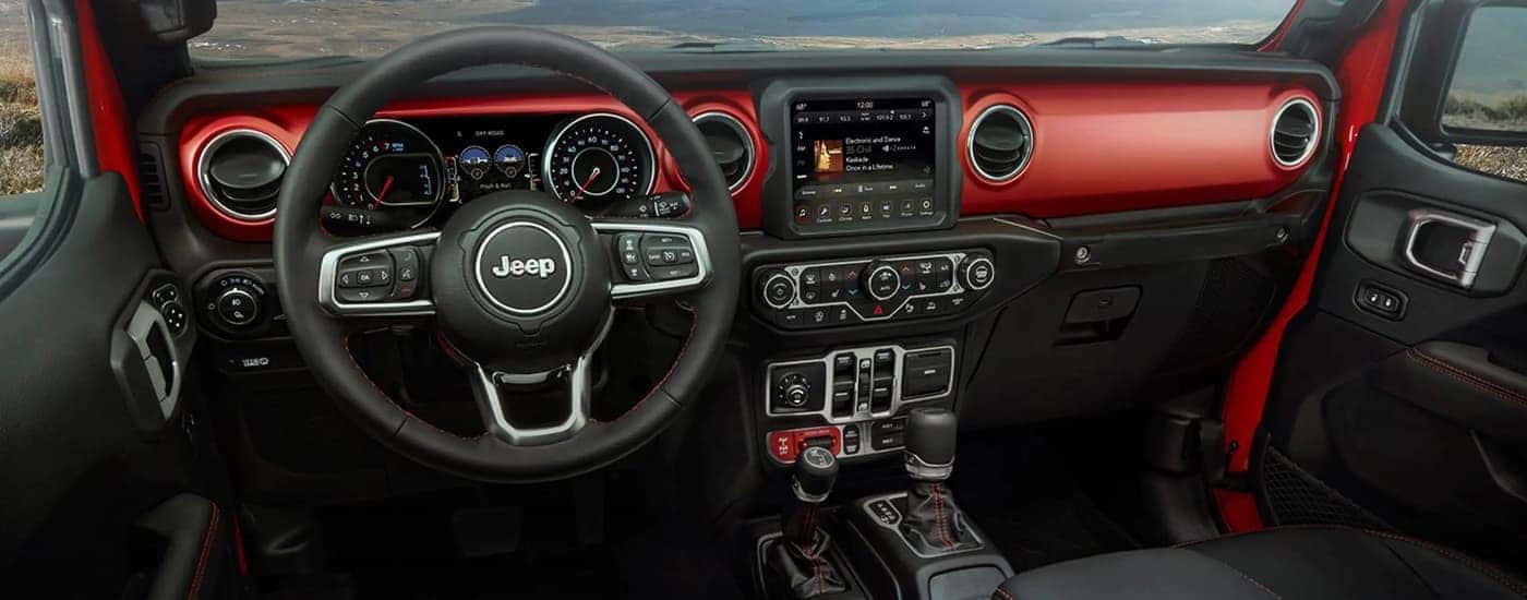 The black and red interior of a 2023 Jeep Gladiator shows the steering wheel and center console.
