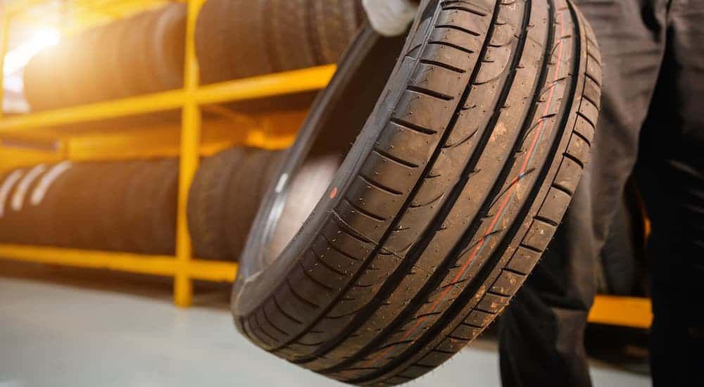 A mechanic is shown carrying a tire.
