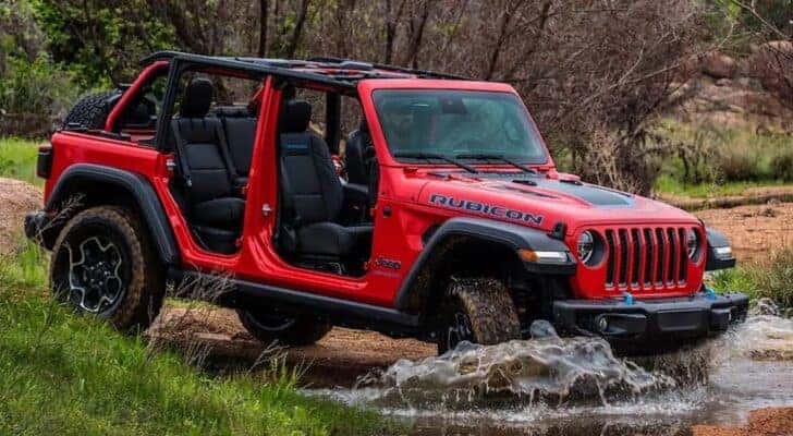 A red 2023 Jeep Wrangler Rubicon 4xe is shown from the side after leaving a dealer that has a Jeep Wrangler for sale.