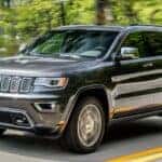 A gray 2020 Jeep Grand Cherokee is shown driving on a highway after visiting a used Jeep Wrangler for sale near Castle Rock, CO.