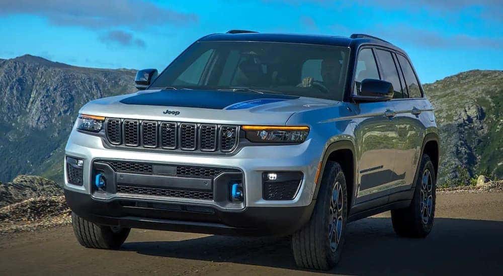 A silver 2022 Jeep Grand Cherokee 4xe is shown from the front at an angle after leaving a dealer that has a Jeep 4xe hybrid for sale.