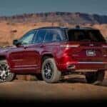 A red 2023 Jeep Grand Cherokee is shown from the rear at an angle.