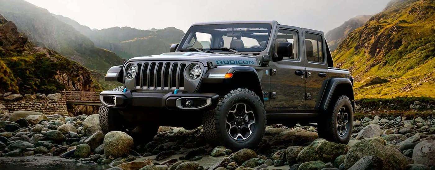 A grey 2022 Jeep Wrangler 4xe is shown from the side parked off-road.