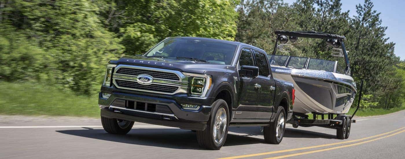 A grey 2022 Ford F-150 is shown from the front at an angle while towing a boat.