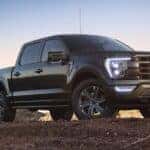 A popular used Ford F-150 for sale, a black 2021 Ford F-150, is shown parked on a dirt hill.