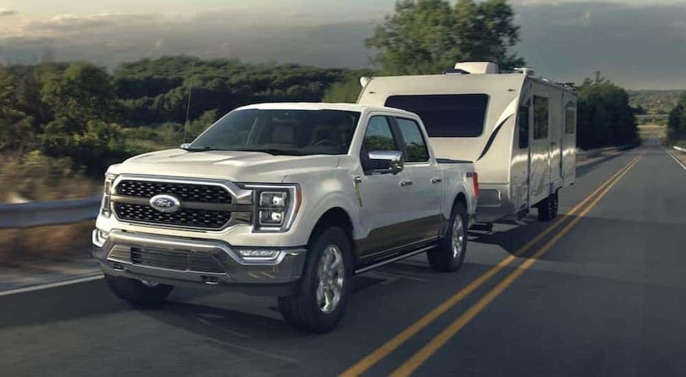 A white 2021 Ford F-150 is shown towing a trailer.